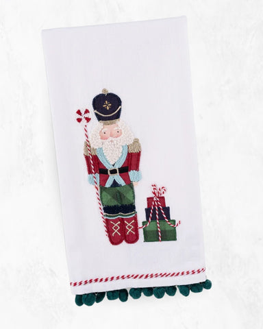 Decorative towel with a Christmas-themed Nutcracker, holding candy canes and presents, on a white background.